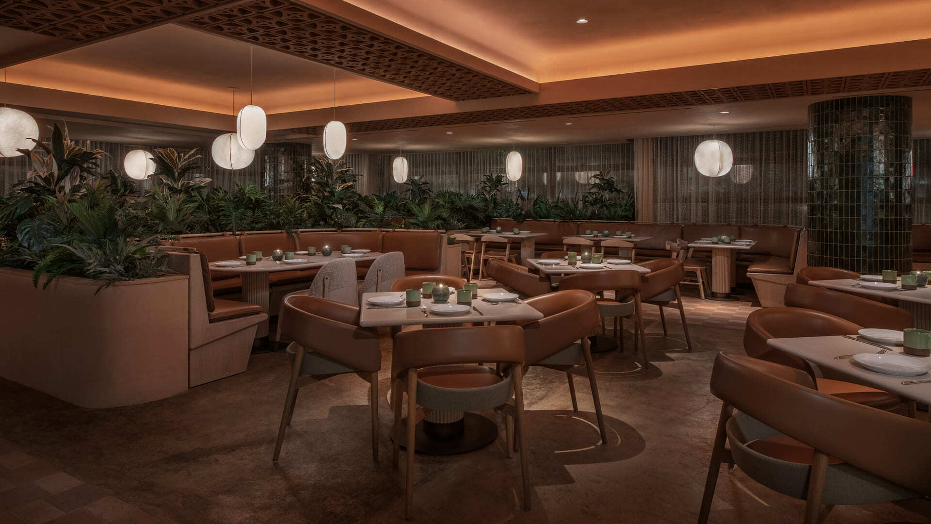 Casa Dani dining area featuring tan leather seating, round tables set with minimalist dinnerware, hanging globe pendant lights, and lush green plants dividing the booths.